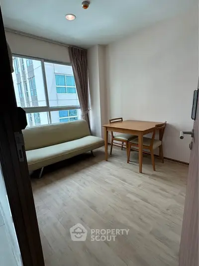 Cozy living room with natural light, featuring a sofa and dining table, perfect for relaxation and dining.