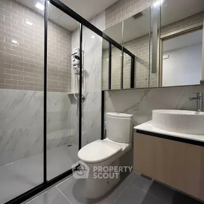 Modern bathroom with glass shower, sleek tiles, and contemporary fixtures.
