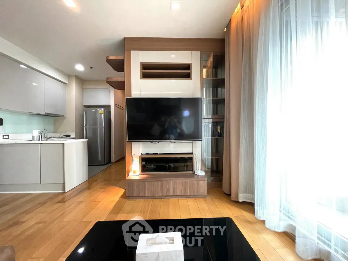 Modern living room with open kitchen, featuring sleek design and natural light.