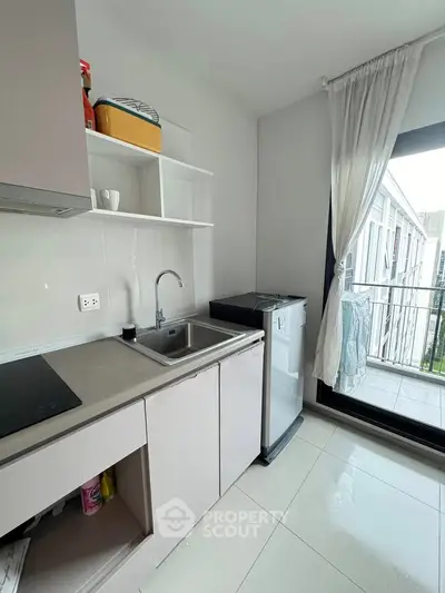 Modern kitchen with sleek cabinetry and balcony view, ideal for urban living.