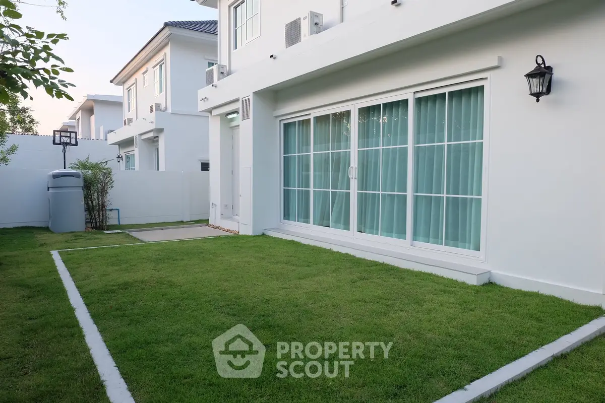 Modern white house with lush green lawn and sliding glass doors, perfect for family living.