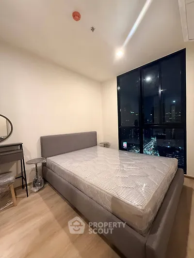 Modern bedroom with city view, featuring a stylish bed and elegant decor.