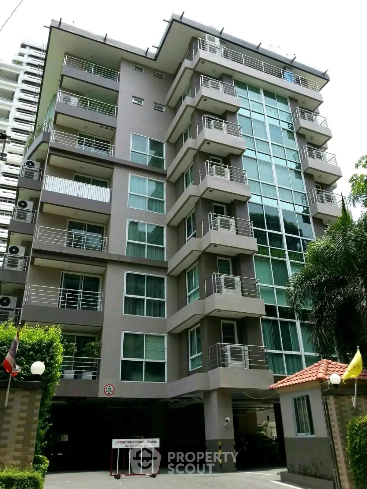 Modern multi-story apartment building with balconies and lush greenery.