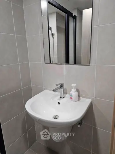 Modern bathroom with sleek sink and mirror in stylish tiled setting