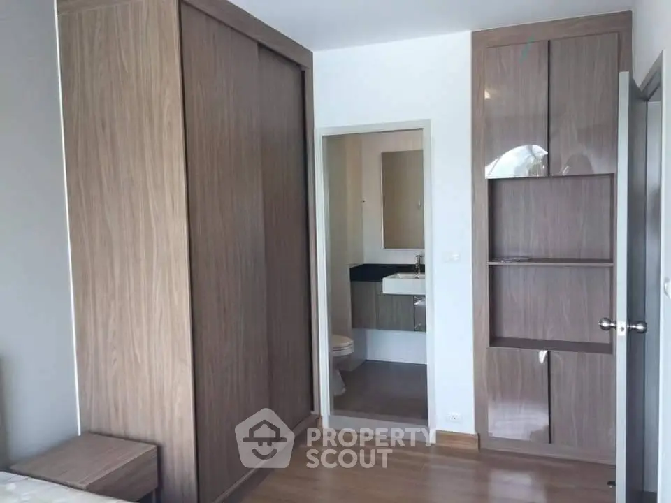 Modern bedroom with wooden wardrobe and ensuite bathroom in stylish apartment.