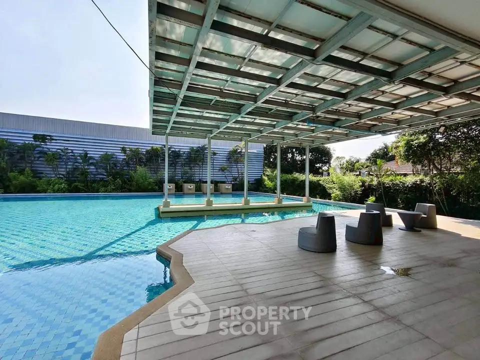 Luxurious outdoor pool area with modern seating and shaded canopy, perfect for relaxation and leisure.