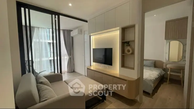 Modern living room with cozy sofa and TV, adjacent to a stylish bedroom with natural light.