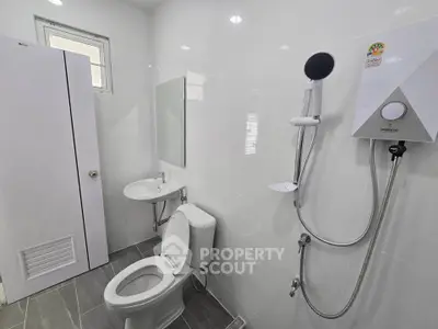 Modern bathroom with sleek fixtures and white tiles, featuring a shower and toilet.