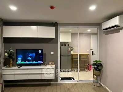 Modern living room with sleek TV unit and view into stylish kitchen.