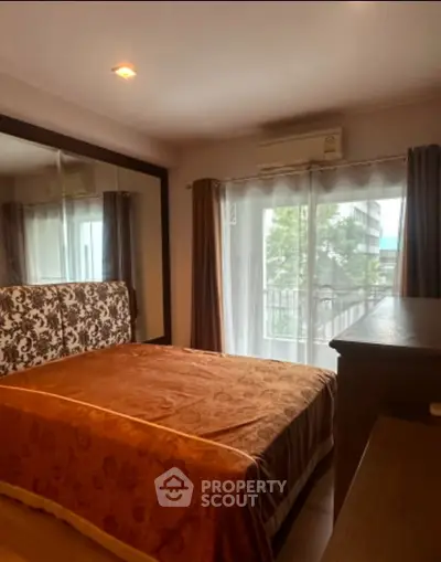 Cozy bedroom with large mirrored wardrobe and balcony view, perfect for relaxation.