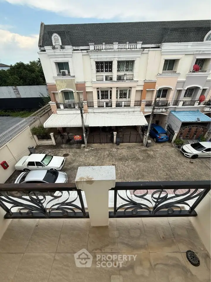Charming townhouse view from balcony overlooking parking area and neighboring building.