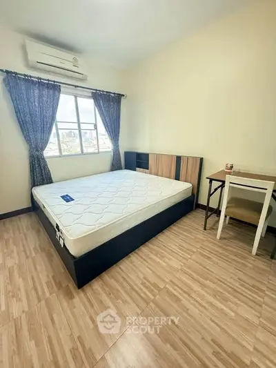Cozy bedroom with large window and modern furnishings, perfect for relaxation and comfort.