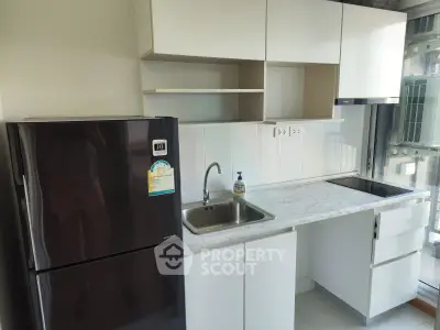 Modern kitchen with sleek cabinets, marble countertop, and stainless steel sink in a compact layout.