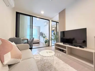 Modern living room with sleek design and open layout leading to a cozy bedroom.