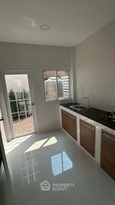 Modern kitchen with sleek design and natural light, featuring closed layout and gas stove.