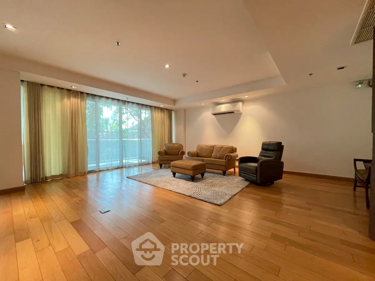Spacious living room with hardwood floors and large windows in modern apartment