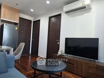 Modern living room with sleek furniture and air conditioning, featuring a flat-screen TV and stylish decor.