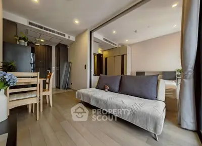 Modern open-plan living room with dining area and cozy bedroom in a stylish apartment.