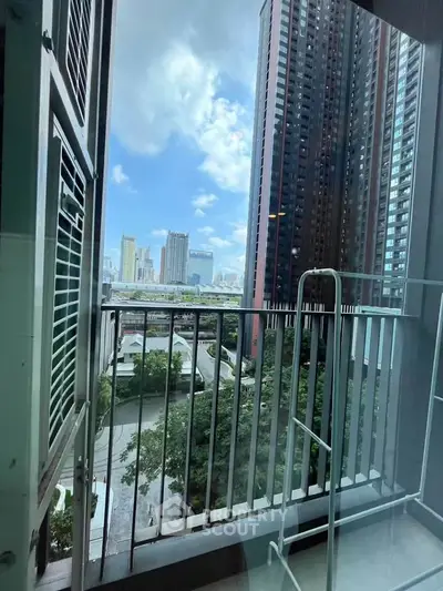 Stunning city view from a modern apartment balcony with high-rise buildings and blue sky.