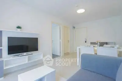 Modern living room with sleek furniture and dining area in a bright apartment.