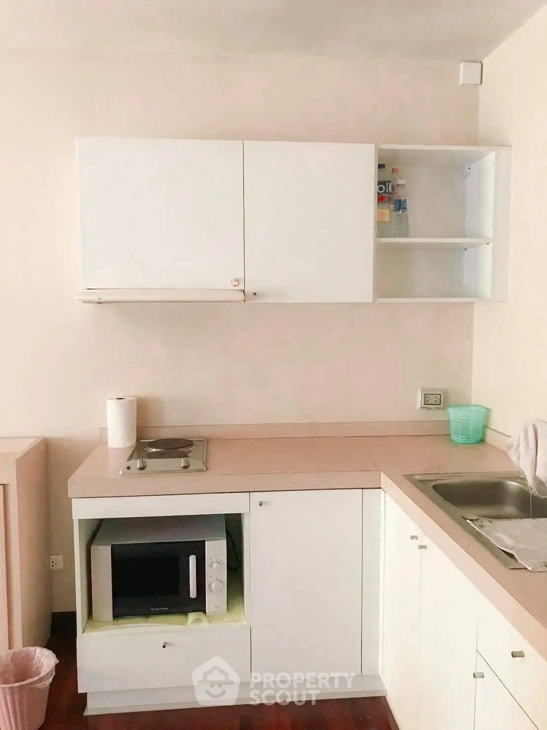 Compact kitchen with white cabinets and built-in microwave