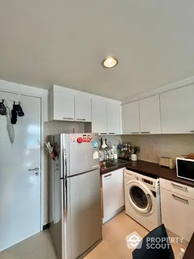 Compact modern kitchen with stainless steel appliances, ample cabinetry, and a convenient layout for efficient cooking in a cozy urban home.