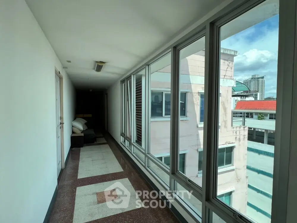 Bright corridor with large windows and city view in modern building.
