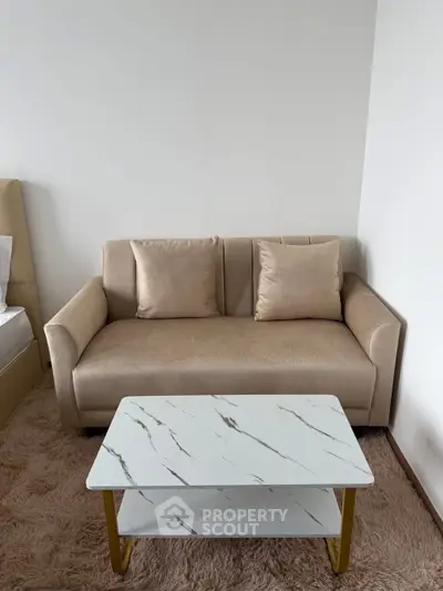 Cozy living room with beige sofa and modern marble coffee table on plush rug.