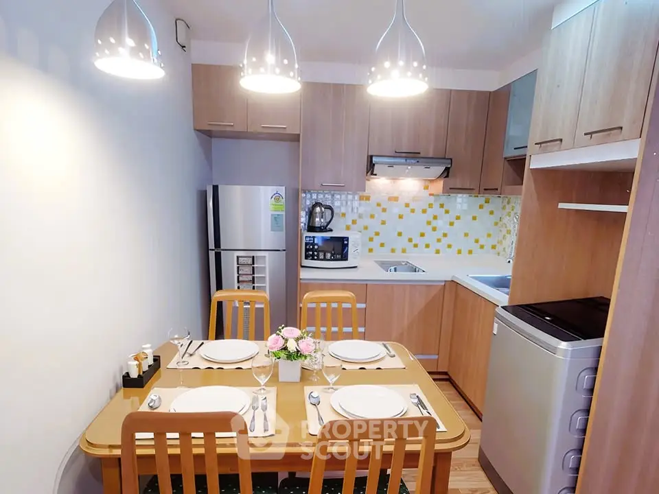 Modern kitchen with dining area, featuring wooden cabinets and stylish lighting.