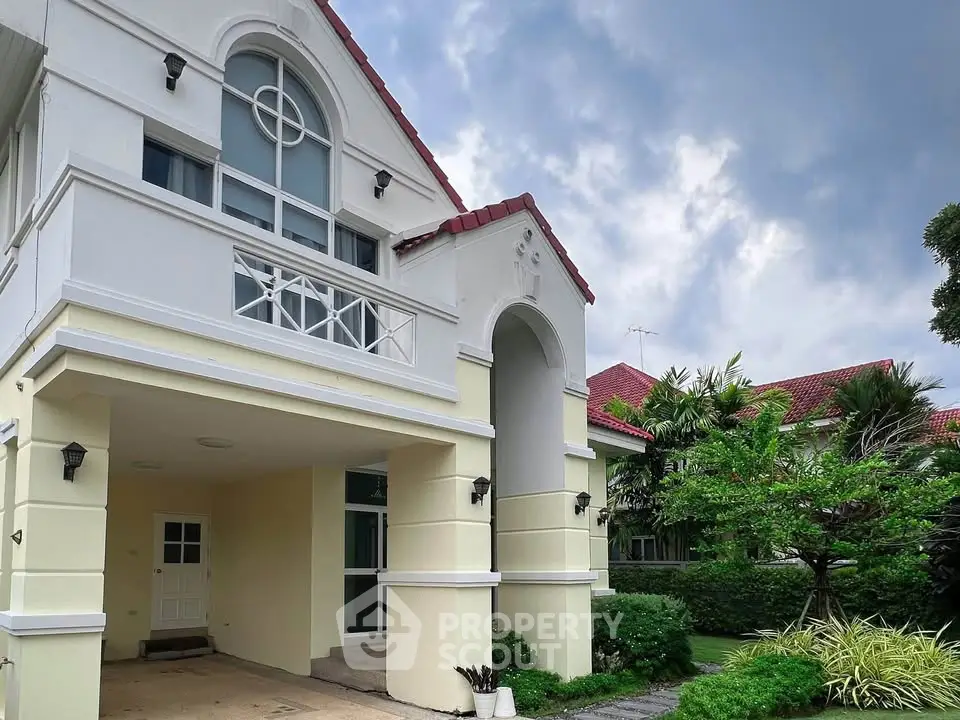 Elegant two-story house with arched entrance and lush garden, perfect for family living in a serene neighborhood.