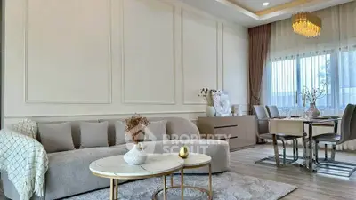 Elegant living room with modern decor and dining area, featuring plush sofa and stylish chandelier.