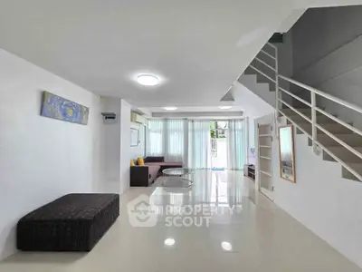 Spacious modern living room with sleek staircase and ample natural light