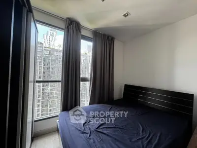 Cozy bedroom with large window offering stunning city views in modern apartment.
