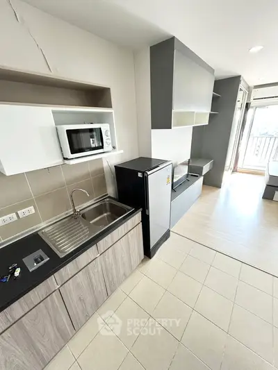 Modern compact kitchen with microwave and fridge in a stylish apartment