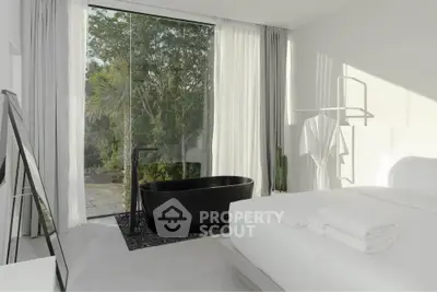Luxurious bedroom with a modern black bathtub and floor-to-ceiling windows offering serene garden views.