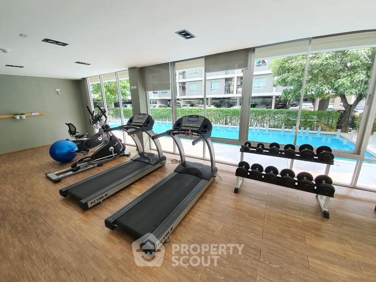 Modern gym with treadmills and pool view in luxury condo