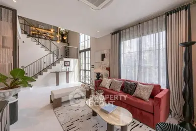 Luxurious living room with high ceilings, elegant staircase, and stylish decor in modern home.