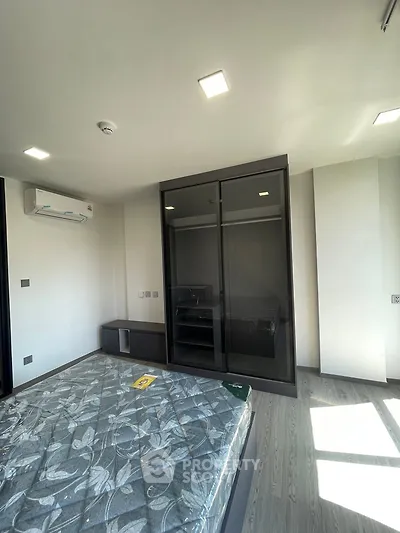 Modern bedroom with sleek wardrobe and air conditioning unit, featuring natural light and stylish flooring.