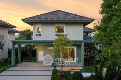 Modern two-story house with landscaped garden and driveway at sunset.