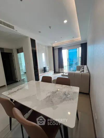 Modern living room with marble dining table and large windows offering city views.