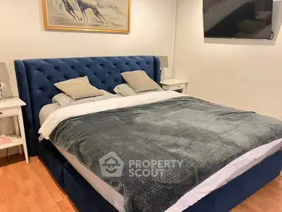 Luxurious bedroom with plush blue headboard and cozy bedding, perfect for relaxation.