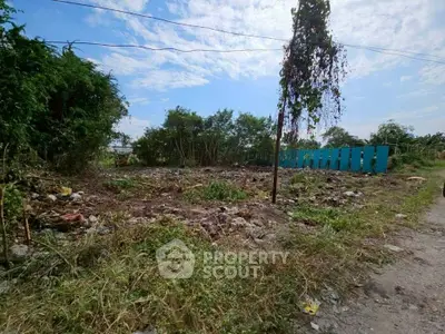 Vacant land plot with potential for development, surrounded by greenery and clear blue skies.
