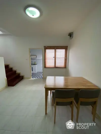 Cozy dining area with wooden table and chairs, adjacent to a modern kitchen.