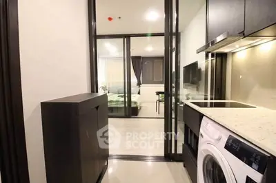 Modern apartment interior with sleek kitchen and view into cozy bedroom
