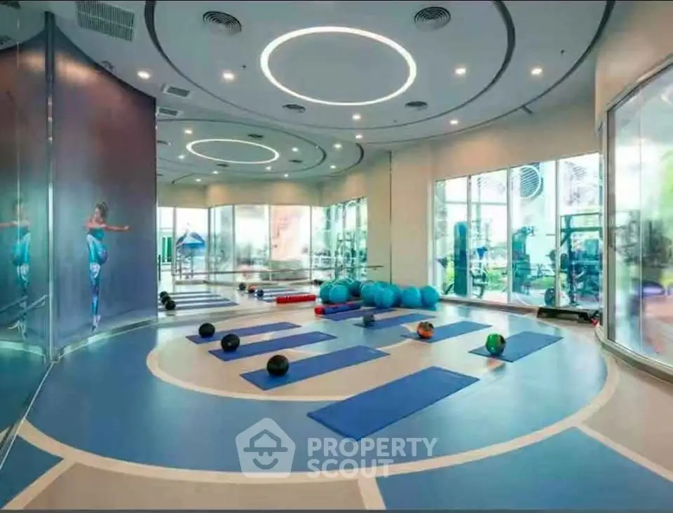 Modern gym with yoga mats and exercise equipment in luxury building