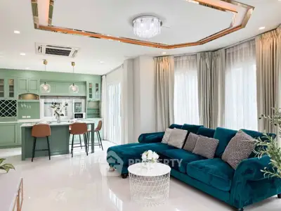 Luxurious open-plan living room with teal sofa and modern kitchen in elegant home.