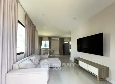 Spacious modern living room with sleek furniture and large TV, perfect for relaxation.