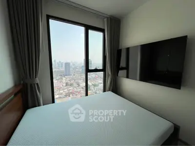 Modern bedroom with large window offering stunning city view and wall-mounted TV.