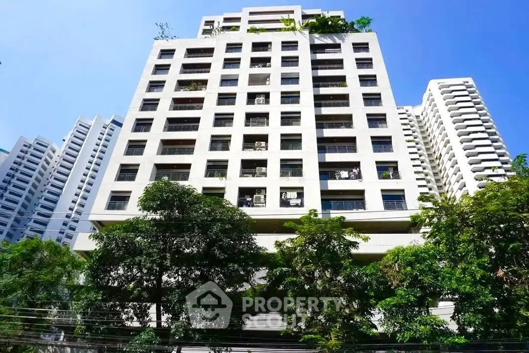 Modern high-rise building with lush greenery and clear blue sky