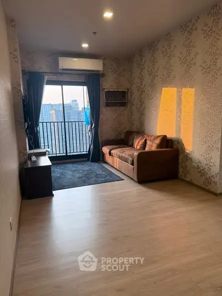 Spacious living room with balcony and city view, featuring modern decor and ample natural light.